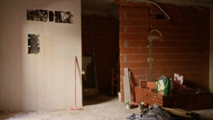 Blurry view of an unfinished construction site with a defocused background, showing building materials and tools scattered around.