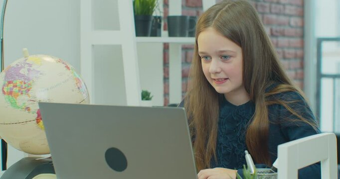 Young girl making facetime video calling with laptop at home, using online class meeting app, social distancing, lockdown, homeschooling, learning remotely, new normal concept.