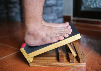 A boy stands on a stretching stick to loosen his muscles, stretch his leg tendons, and tighten his...