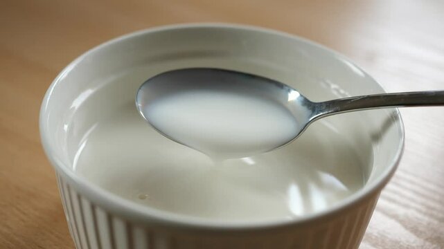 scooping milk with a spoon from a breakfast bowl full of milk