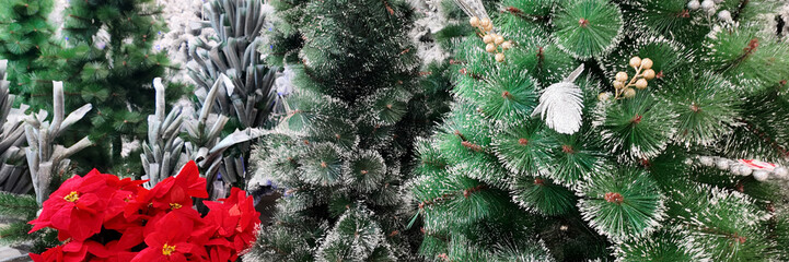 Festive artificial Christmas trees adorned with snow-dusted branches and vibrant red poinsettias highlight holiday decoration ideas and seasonal cheer