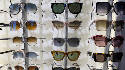 A diverse display of stylish sunglasses on a rack, ideal for promoting summer fashion and eye...