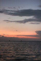 peaceful evening sky with hues of orange and purple. The sun dips below the horizon, casting a warm glow on the calm waters