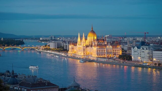 Breathtaking view of the Hungarian Parliament with street lights glowing and boats gently drifting on the Danube River, capturing the city's evening charm