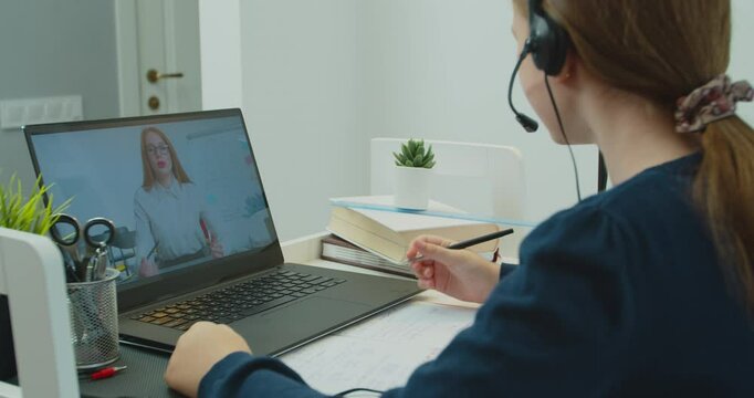School girl wearing headphones college student distance learning virtual distance online lesson on video call with teacher tutor studying at home. Online distance learning education lesson concept.