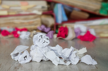 Crumpled paper balls and messy file folders,overworked,bureaucracy,burnout syndrome,business concept, blurred background,shallow depth of field, close up shpt