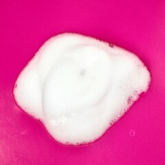 Foamy hand wash swatch texture isolated on square pink colored background from above angle view.