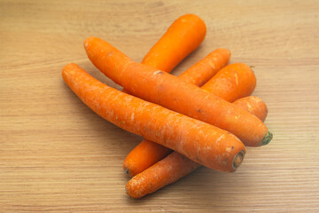 Fresh carrots on a wooden kitchen countertop, vibrant orange hues, arranged neatly in a rustic kitchen setting with soft indoor lighting.
