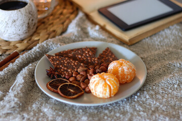 Books, e-reader, tea, orange juice, fruit, snacks, yarn, blanket and lit candles on the table....