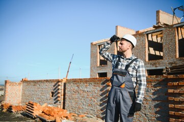 construction mason worker bricklayer installing red brick with trowel putty knife outdoors