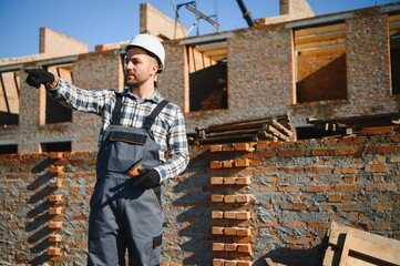construction mason worker bricklayer installing red brick with trowel putty knife outdoors
