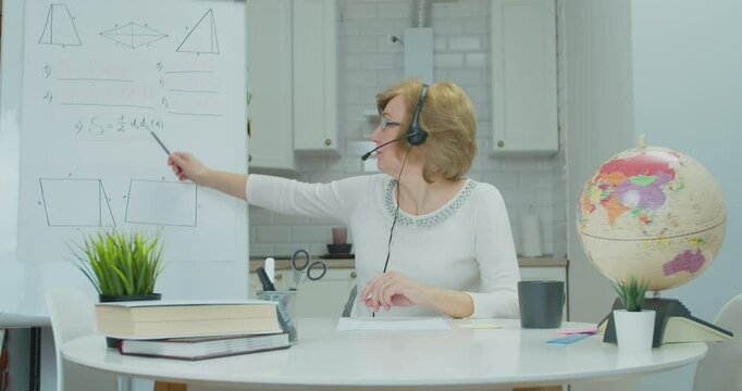 The teacher leads an online lesson for schoolchildren or students. Adult woman in headphones talking to students via video conference at home. Distance Learning, e-education, e-Learning, homeschooling