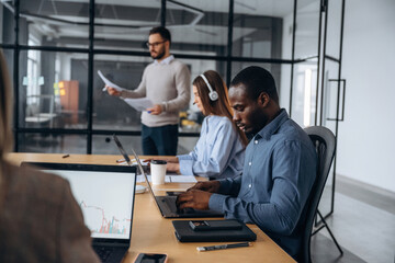 Wireless devices, laptops on the table. Professional workers are in the modern office together