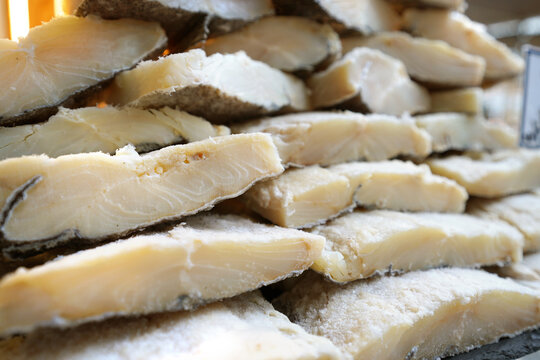 A stack of traditional dried and salted codfish (bacalhau) on display, ready for use in authentic Portuguese and Mediterranean dishes.