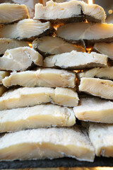 Close-up of high-quality salted cod, showcasing its delicate texture and golden tones under warm lighting. Perfect for holiday recipes or Portuguese classics.