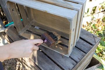 a child paints a wooden box with brushes in the garden