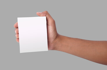 Hand holding a blank white card against a plain gray background.