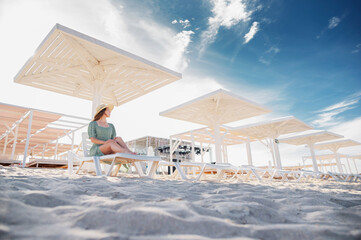 Beautiful woman relaxing in sunbed at luxury tropical beach in a sunny summer day