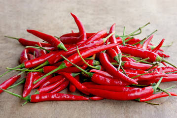 Red chili peppers placed on a wooden table, taken from the front.