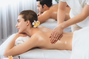 Obraz premium Caucasian couple customer enjoying relaxing anti-stress spa massage and pampering with beauty skin recreation leisure in day light ambient salon spa at luxury resort or hotel. Quiescent