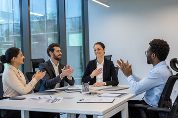 A diverse group of professionals is seen applauding during a successful business meeting. The office setting reflects teamwork, motivation, and corporate culture, highlighting collaboration.