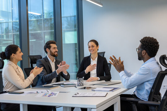 A diverse group of professionals is seen applauding during a successful business meeting. The office setting reflects teamwork, motivation, and corporate culture, highlighting collaboration. - Powered by Adobe