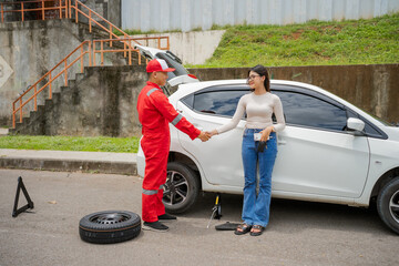 A mechanic helps a woman with a flat tire, highlighting the value of assistance in emergencies