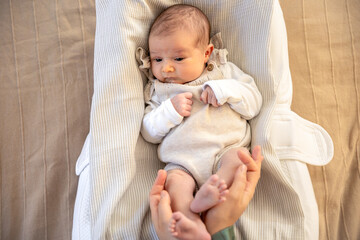 Parent holding in the hands feet of newborn baby. Mom holding baby feet.