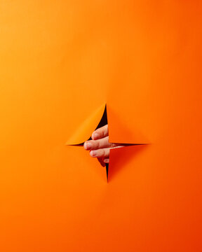 Woman's hand poked through orange background