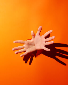 Empty woman's hands poked through orange background