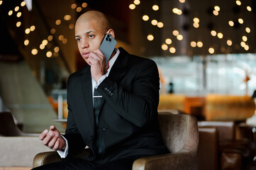 African american businessman in suit talking on cellphone in business center