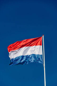 Dutch flag flies in the blue sky of amsterdam