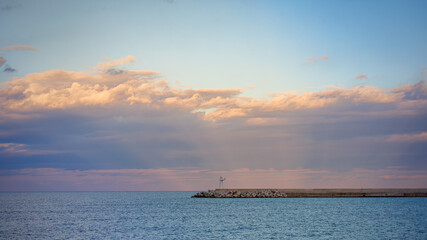 Obraz premium White lighthouse on breakwater, rough waves, and cloud shadows