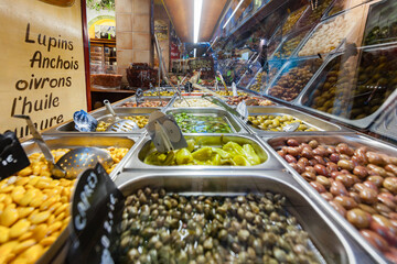 NICE, FRANCE: woman buying olives and pickles, food speciality in Nice, colorful choice of preparations, freshly homemade
