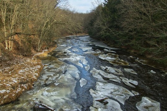 Landscape view from above a partially frozen Eau Claire River passing through a forest on a cloudy Winter day near Aniwa, Wisconsin.