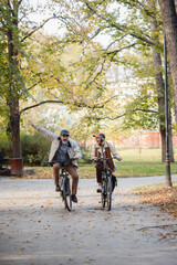 Fototapeta premium Senior couple riding bicycles together through an autumn park, laughing and enjoying an active lifestyle, showcasing fun, health, and companionship in a vibrant outdoor setting