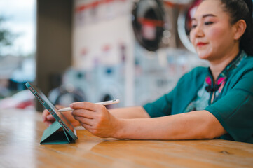 Woman uses tablet with stylus in modern laundry shop, blend of technology and daily chores in...