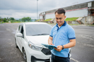 A man is carefully reviewing the navigation details while standing next to a white car