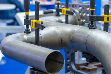Close-up of metal pipes and clamps at a trade show for industrial tech, highlighting engineering...