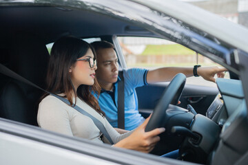 A couple joyfully learns to drive together, focusing on the road as they start this adventure