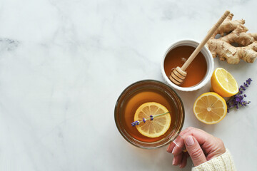 Female hands holding a mug of lemon ginger tea with honey and lavender. 