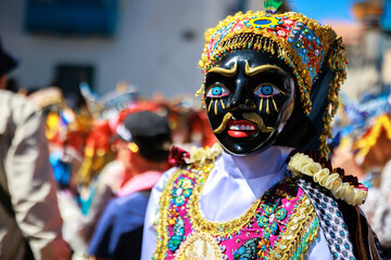 Dancers with masks and traditional costumes celebrate the festivity of the Virgen del Carmen in the...
