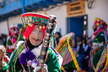 Dancers with masks and traditional costumes celebrate the festivity of the Virgen del Carmen in the square of Paucartambo. Cusco Peru.