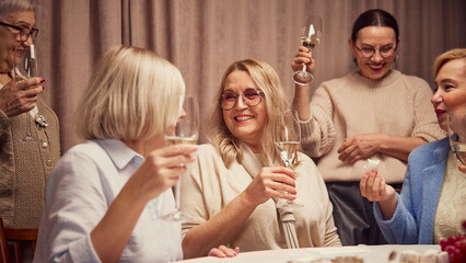 Happy, smiling, elderly people, colleagues, friends drinking wine, laughing and cheerfully talking, discussing news and memories. Concept of elderly lifestyle, positive emotions