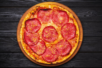 Salami pizza close up on dark wooden table with copy space, top view