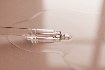 Pipette with oil or serum on a golden background.