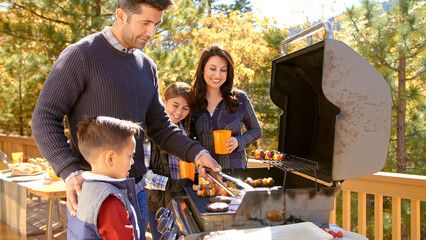 Family Outdoors At Home Enjoying Autumn Or Fall Barbecue Together