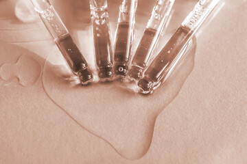 Pipettes with oil or serum on a golden background.