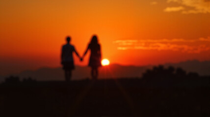 Romantic couple holding hands at sunset with warm orange sky