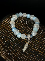 a stylish bracelet made of natural stones with an amulet and inserts made of silver and gold